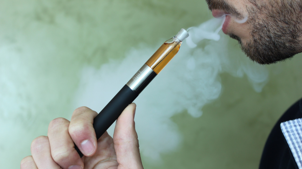 A young man holding a vape.